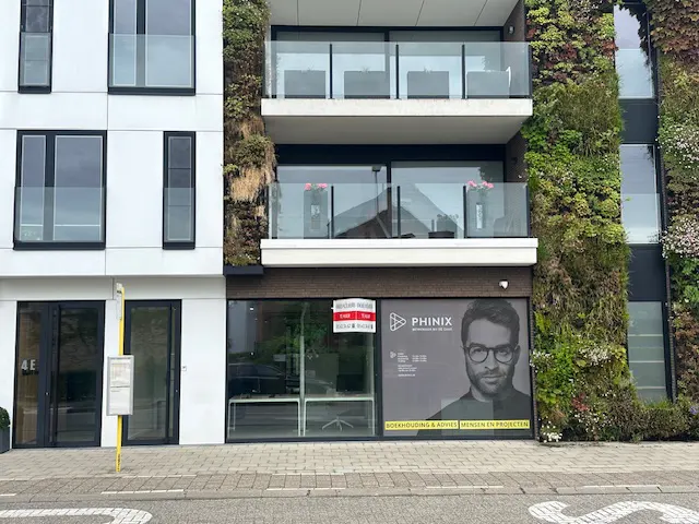 Modern building with green walls and balconies. A "to rent" sign hangs in the window of "Phinix" accounting firm.