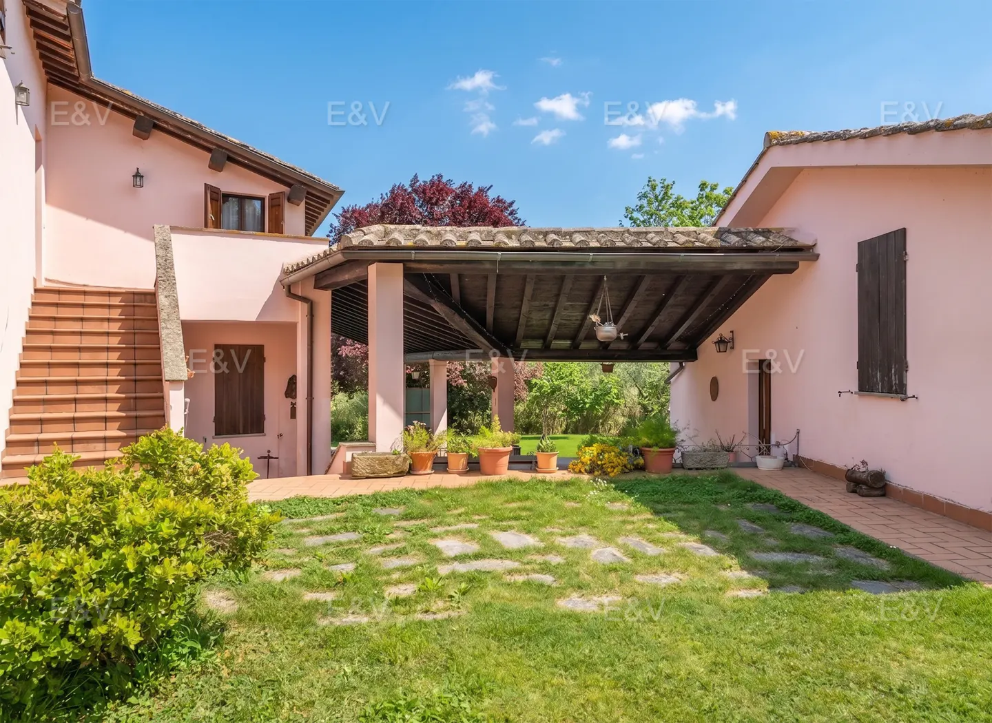 Exterior of a pink two-story house with a covered patio and a green lawn.