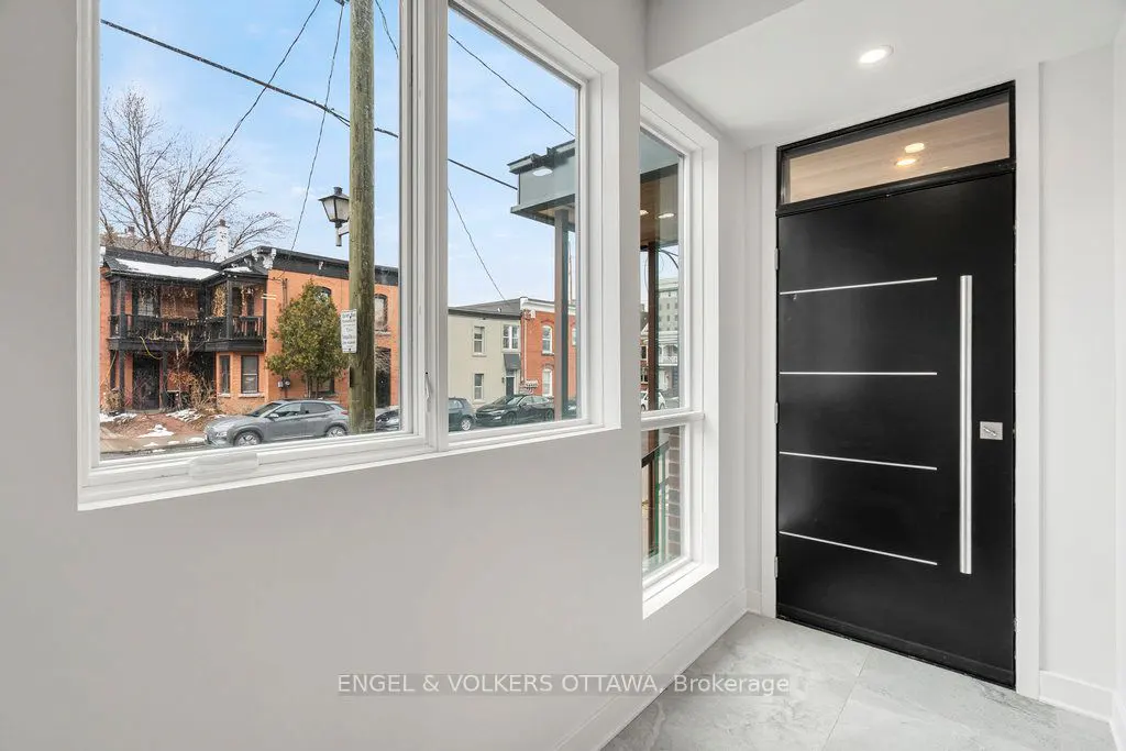 Entryway with a black door and a large window showing a street with brick buildings.