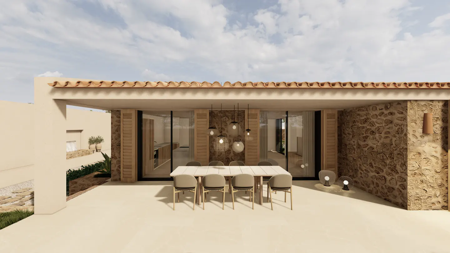 Outdoor dining area with a long table and chairs under a covered patio with stone walls and a terracotta tile roof.