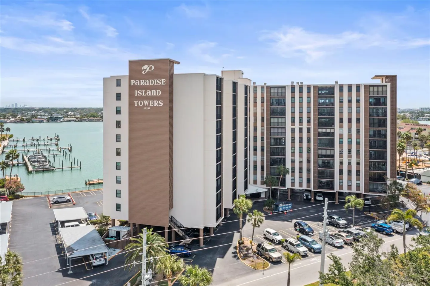 Exterior view of Paradise Island Towers, a multi-story condo building with a marina and parking lot.