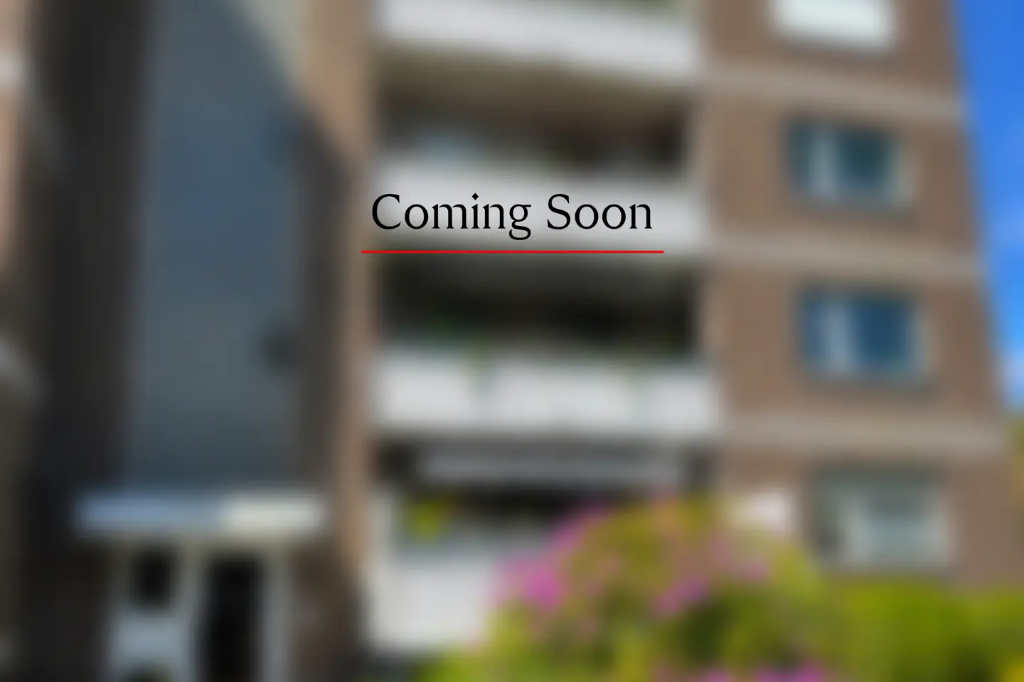 Blurred image of a multi-story apartment building with "Coming Soon" text overlayed in black with a red underline.