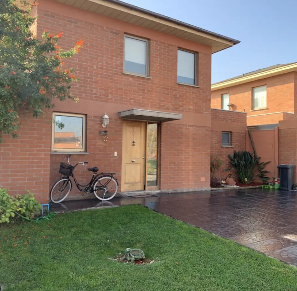 Brick house with an open wooden door, a black bicycle parked outside, and a green lawn.