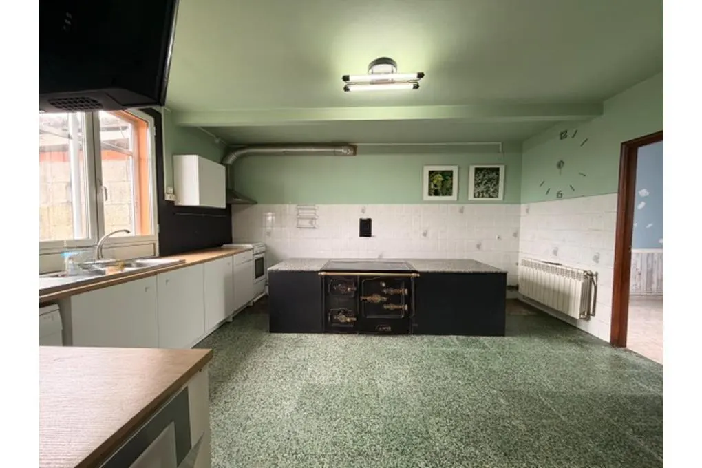 A kitchen with green walls, white cabinets, and a large black island with a vintage stove.
