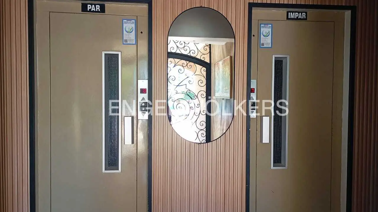 Two elevators, one labeled "PAR" and the other "IMPAR," flank an oval mirror on a wood-paneled wall.