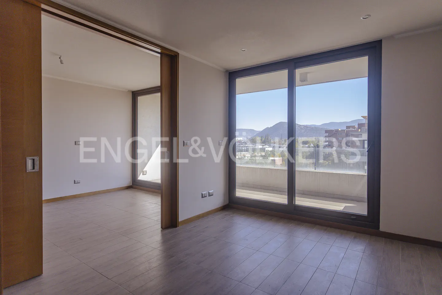 An empty room with wood floors and a large window with a view of mountains.