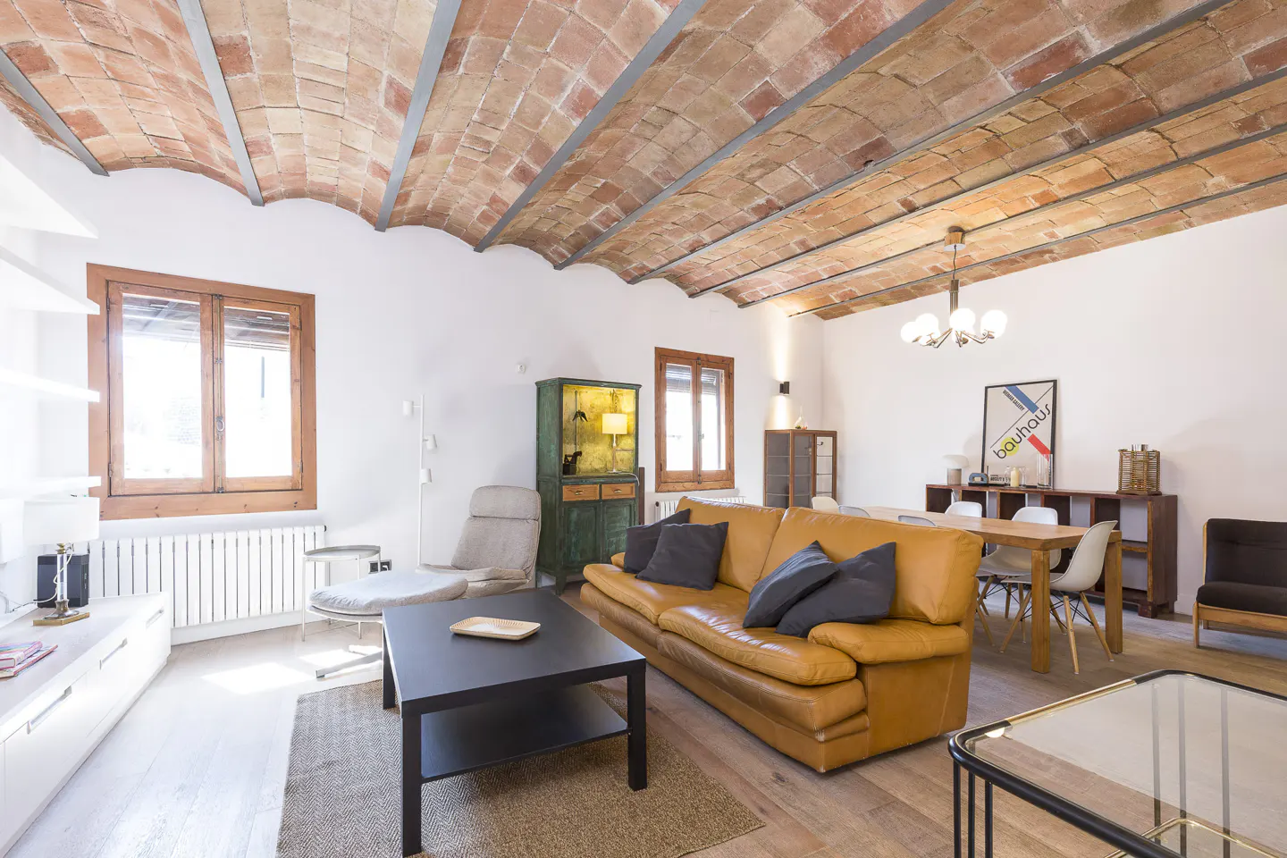 Bright living room with a brick vaulted ceiling, a brown leather sofa, and a black coffee table.