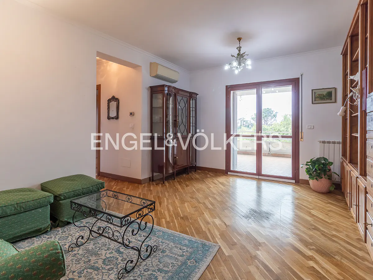 Living room with hardwood floors, green sofa, glass coffee table, and a balcony with a view.
