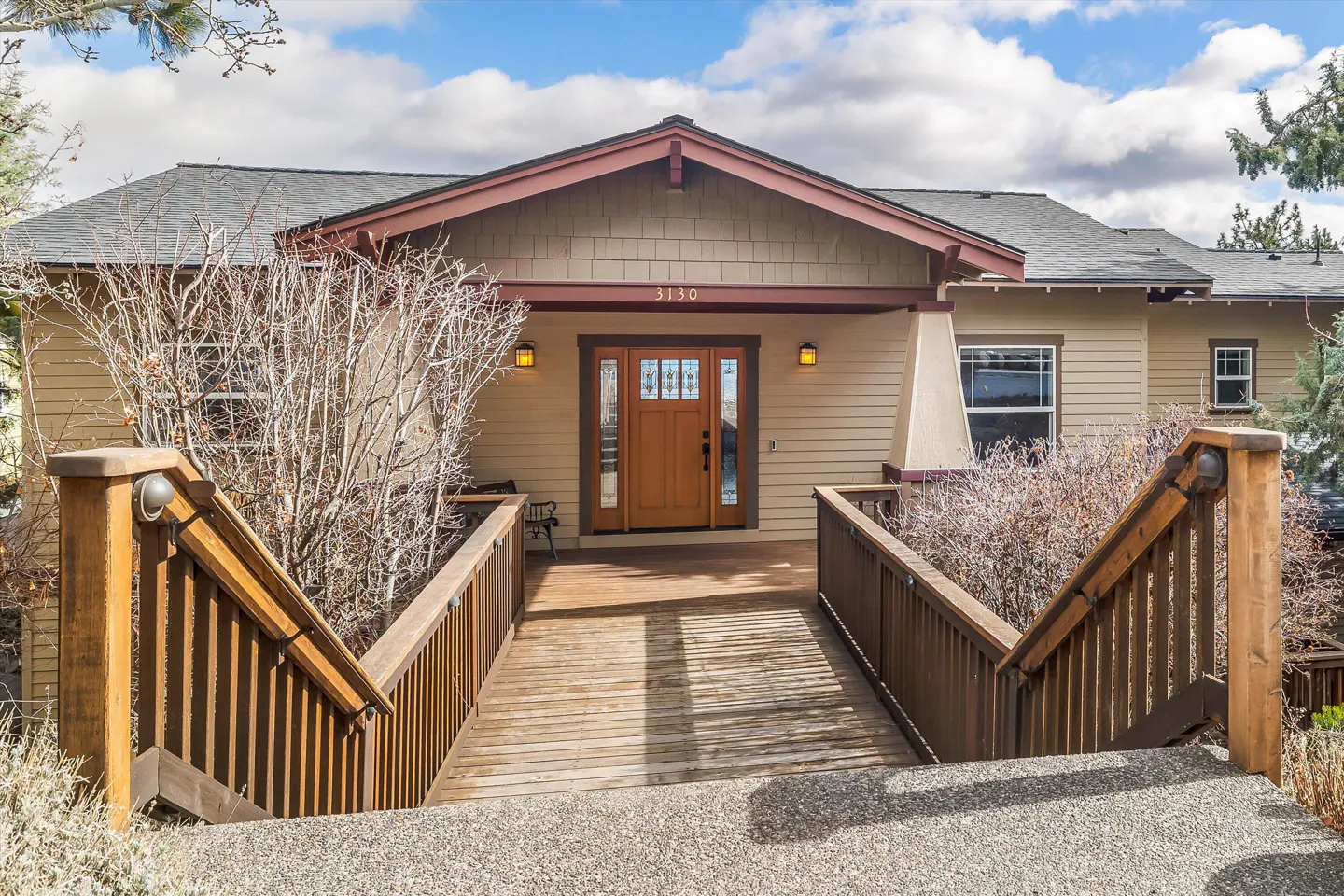 Exterior of a beige house with a wooden ramp leading to the front door. The house number "3130" is above the door.