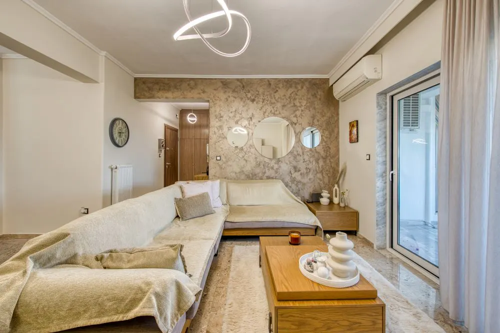 Living room with a beige L-shaped sofa, a wooden coffee table, and three round mirrors on a textured wall.