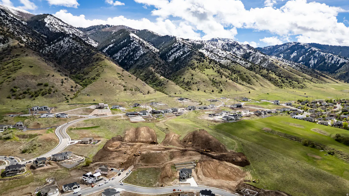 Aerial view of a housing development nestled in a valley with snow-capped mountains in the background.