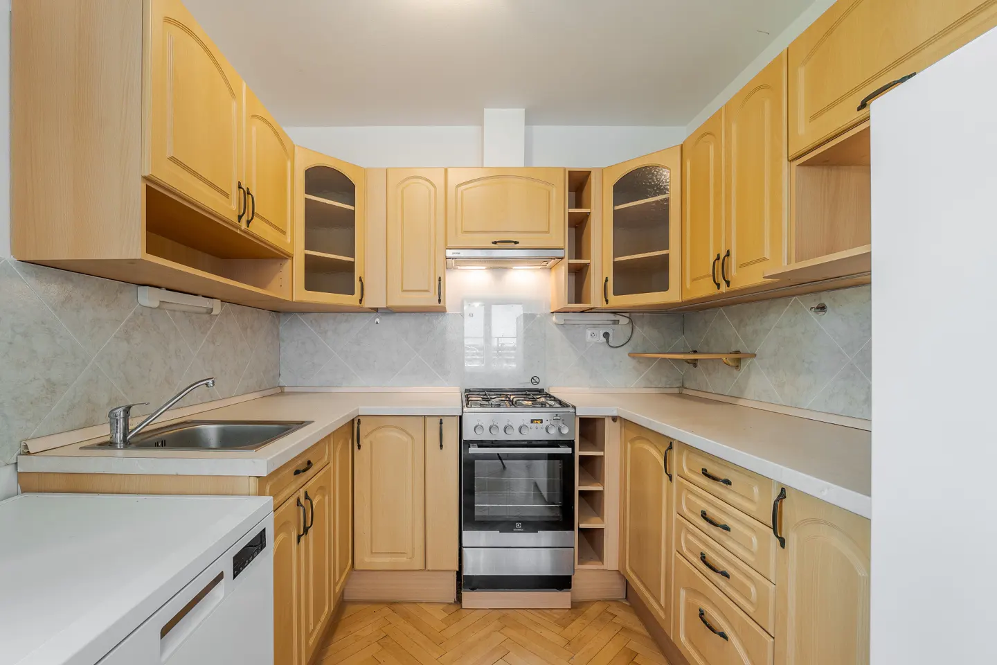 A kitchen with light wood cabinets, white countertops, and stainless steel appliances.