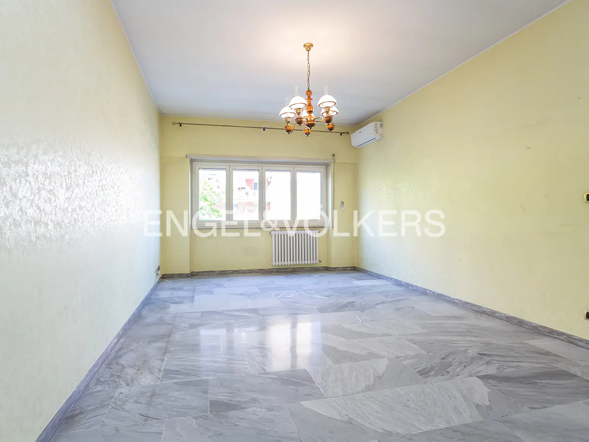 Empty room with marble floors, yellow walls, a window, and a chandelier.
