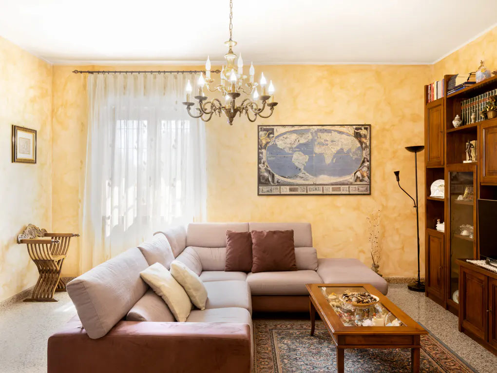 Living room with yellow walls, a beige sectional sofa, a wooden coffee table, and a world map on the wall.
