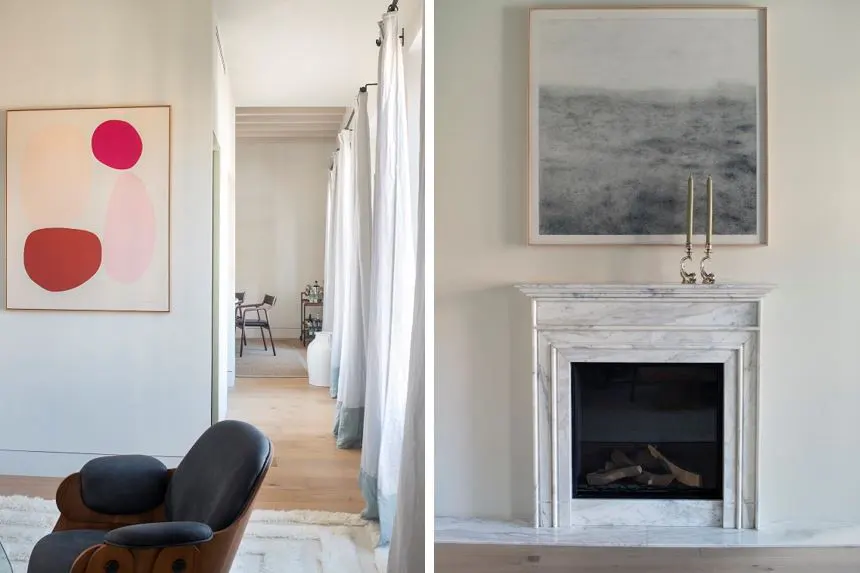 Interior view of a living room with a marble fireplace, abstract art, and a hallway with white curtains.