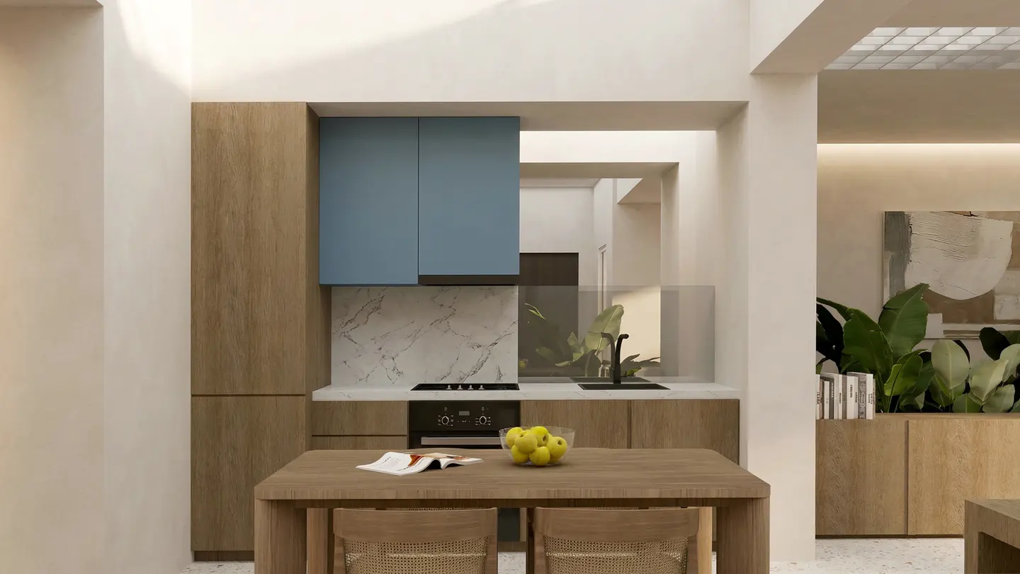 A modern kitchen with light wood cabinets, blue upper cabinets, marble backsplash, and a wood table with apples and a book.