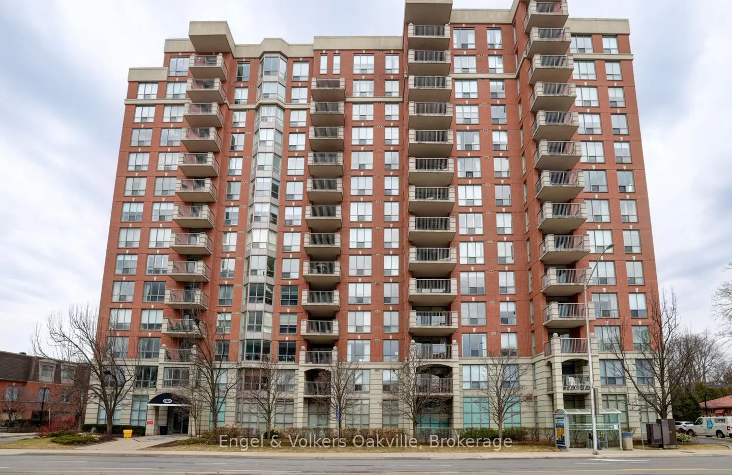 Exterior of a tall red brick condo building with balconies and many windows.