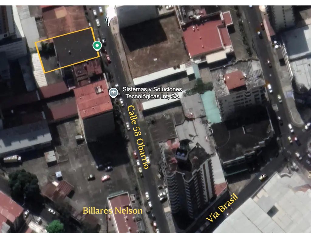 Aerial view of a city block with buildings, streets, and cars. A building is outlined in yellow.