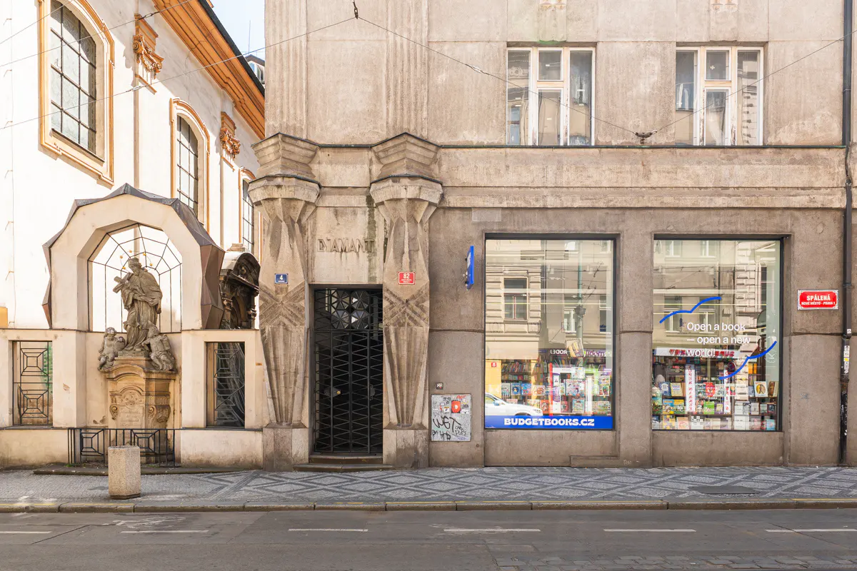 A street view of a historic building with a stone statue niche on the left and a bookstore storefront on the right.