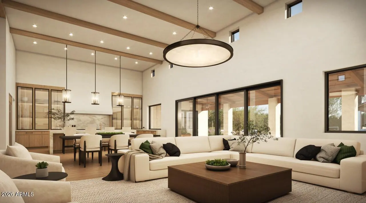 Modern open-concept living room with high ceilings, wooden beams, a large sectional sofa, and a dining area in the back.