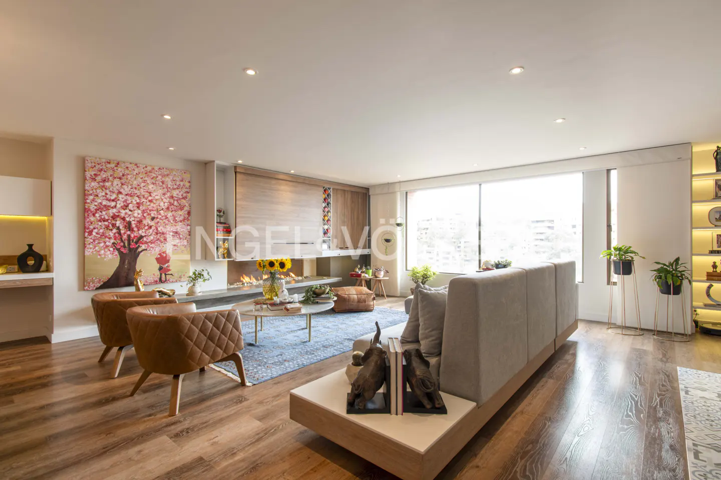 Living room with hardwood floors, a blue rug, and a fireplace. There is a painting of a cherry blossom tree on the wall.