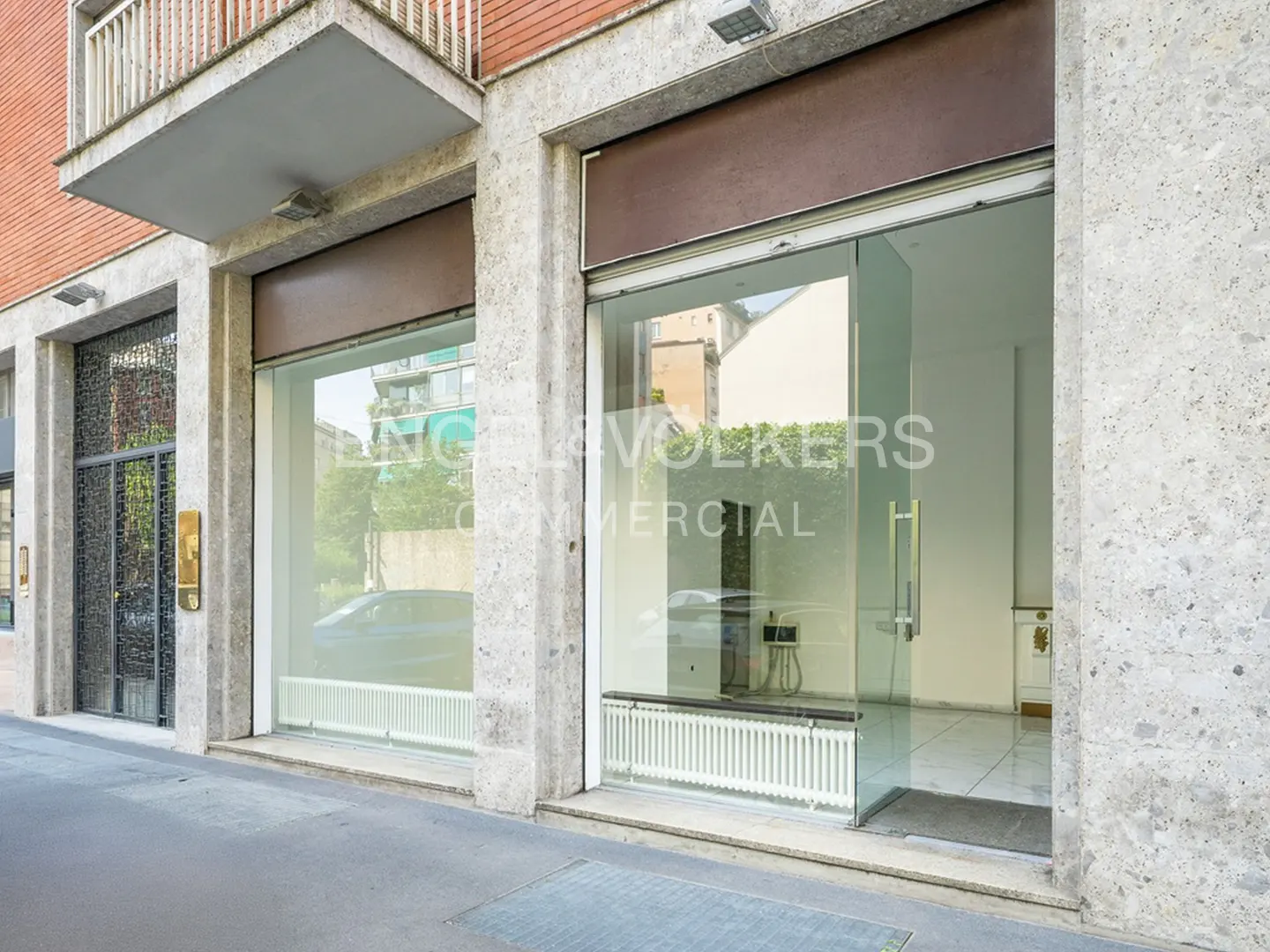 Exterior view of Engel & Volkers Commercial office with glass windows and doors. The building is made of stone and brick.