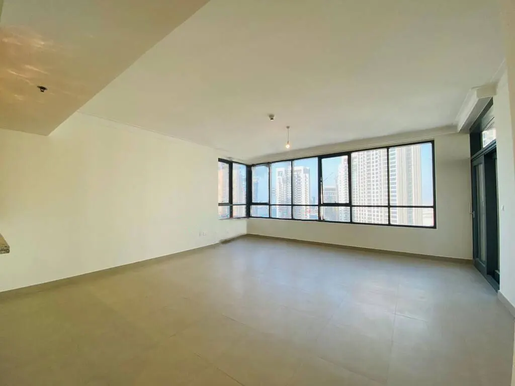 Empty room with tile floor, white walls, and large windows showing a city skyline.