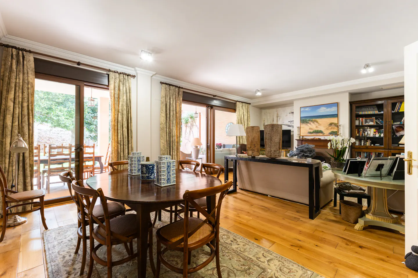 Open-concept living and dining area with wood floors, a round table with chairs, and sliding glass doors to a patio.