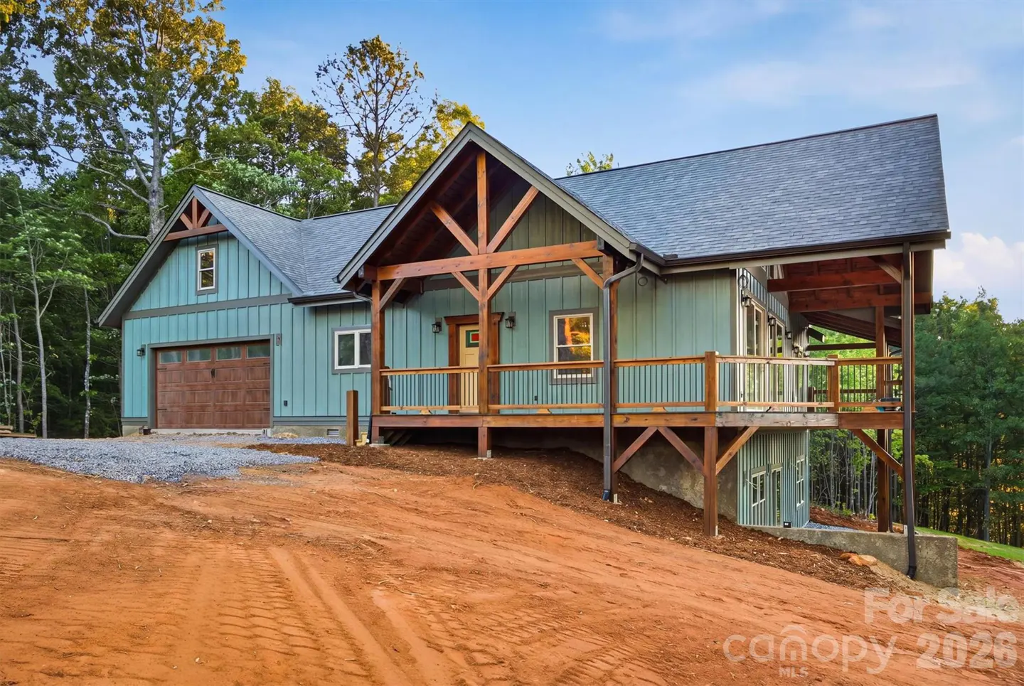Exterior of a light blue, two-story home with a brown garage door and a wooden porch.
