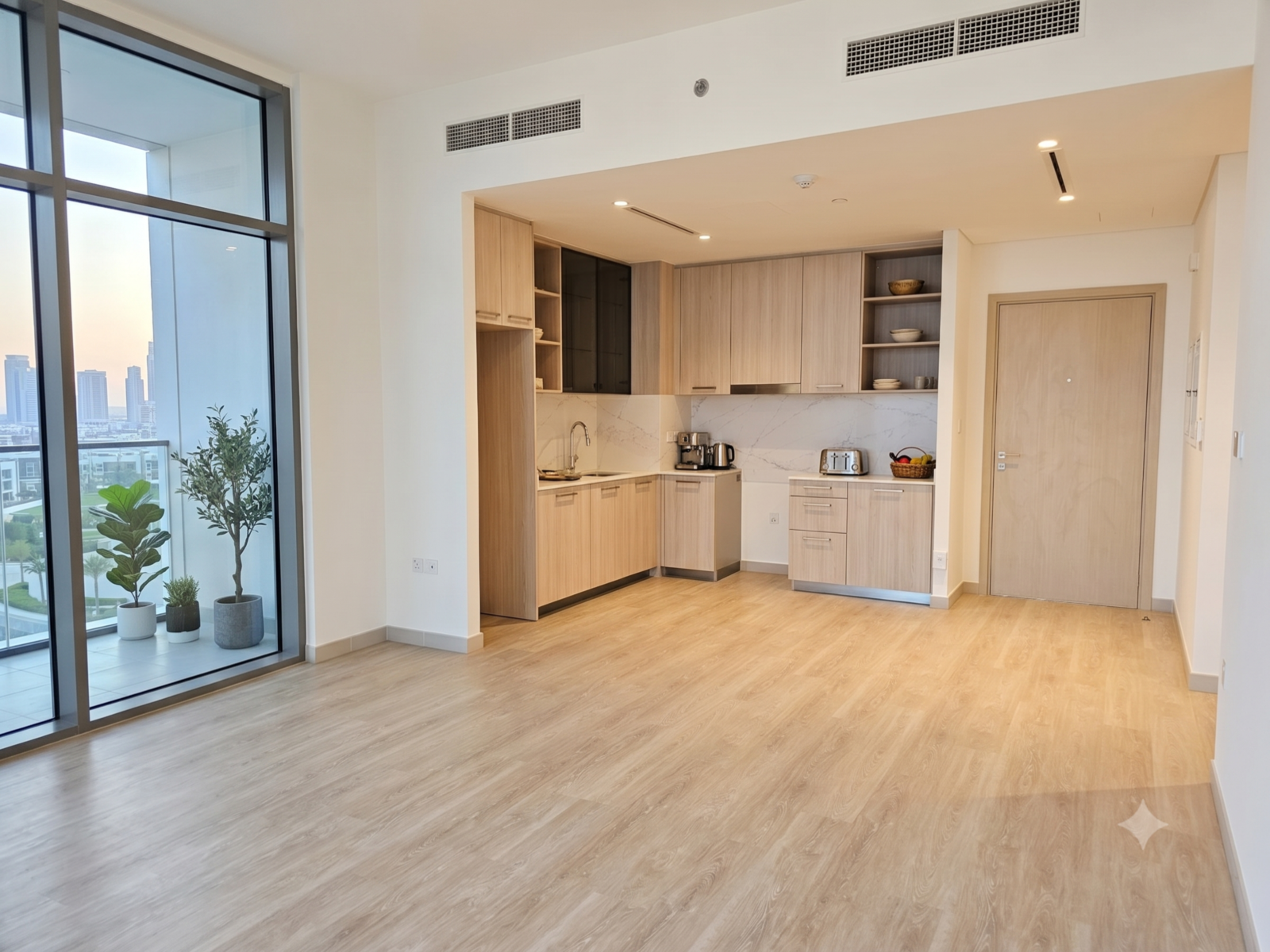 Modern open-plan apartment with light wood floors, a sleek kitchen, and floor-to-ceiling windows overlooking a city view.