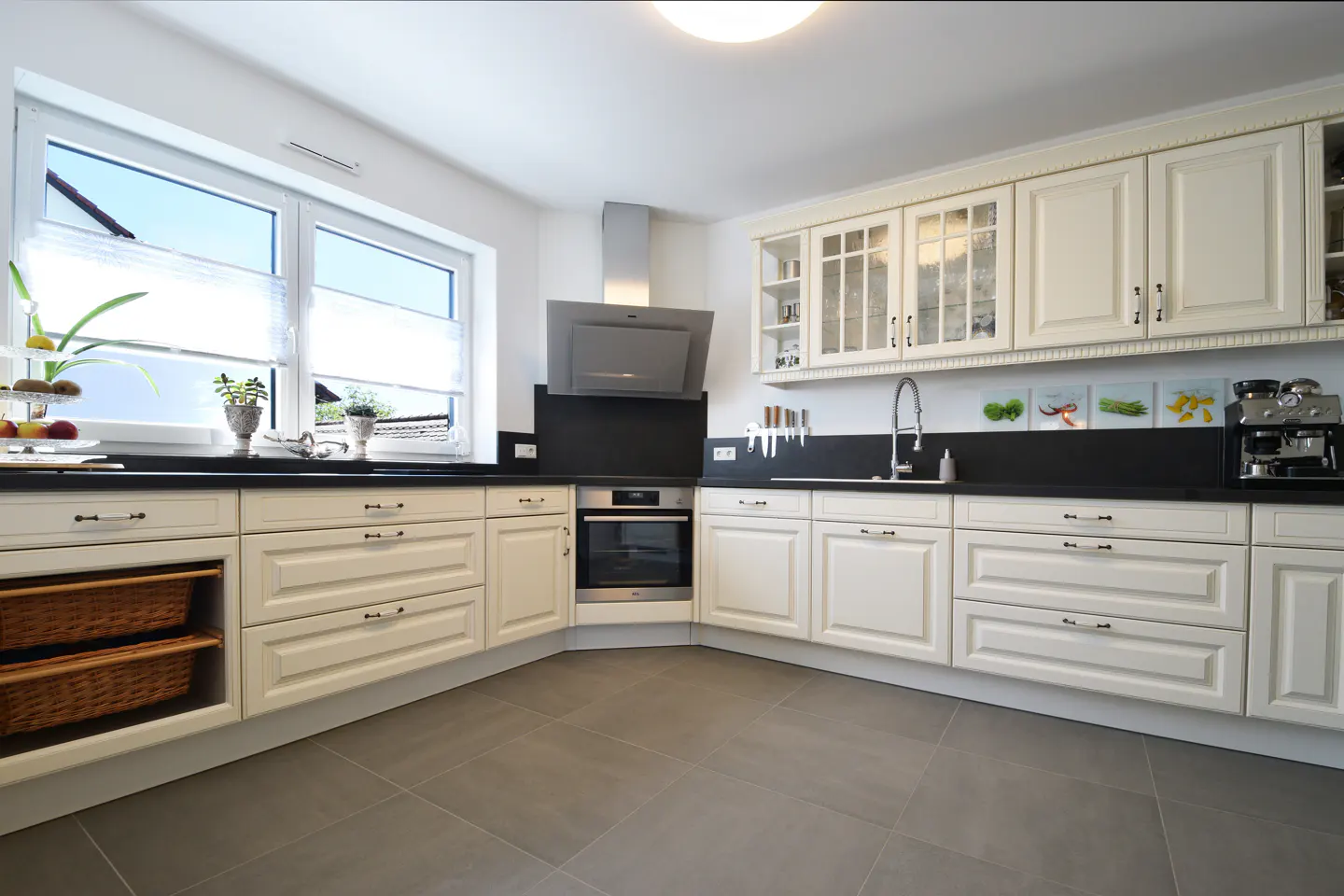 Bright kitchen with white cabinets, black countertops, and gray tile flooring. A window provides natural light.