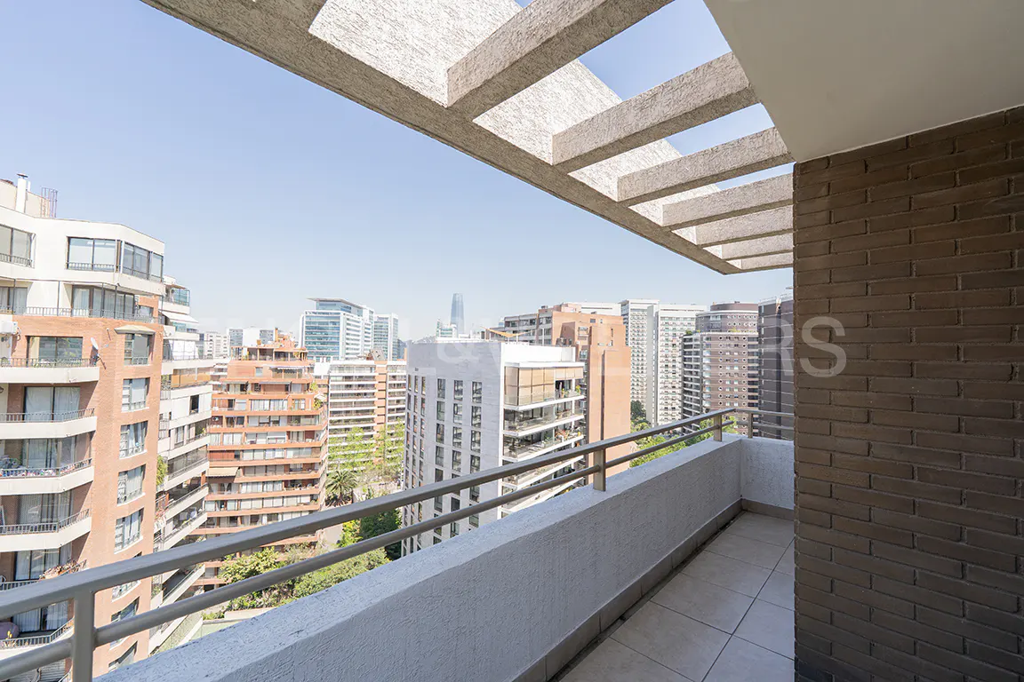 Balcony view of a city skyline. Gray railings and a concrete overhang frame the cityscape with various buildings.