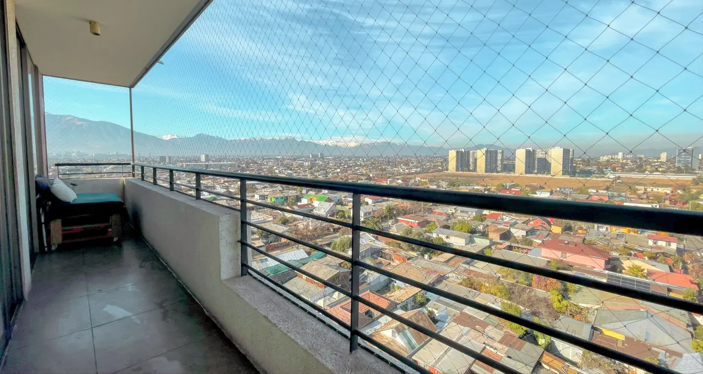 Balcony with a small bench overlooking a sprawling city with distant snow-capped mountains under a clear blue sky.