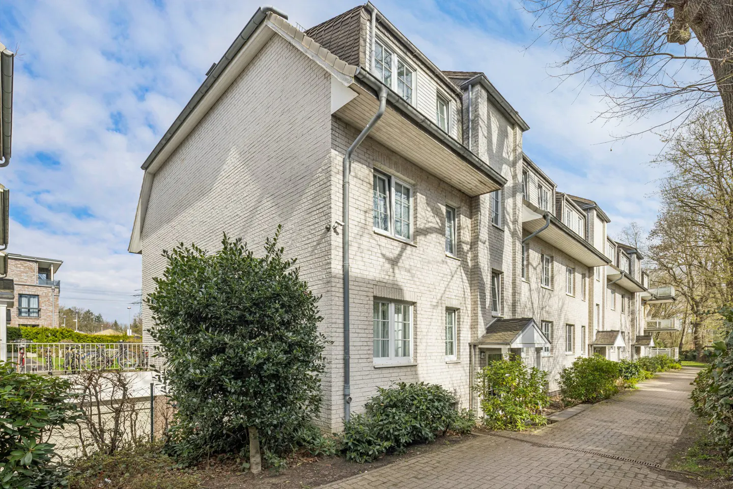Exterior view of a multi-unit apartment building with white brick facade and a brick walkway.