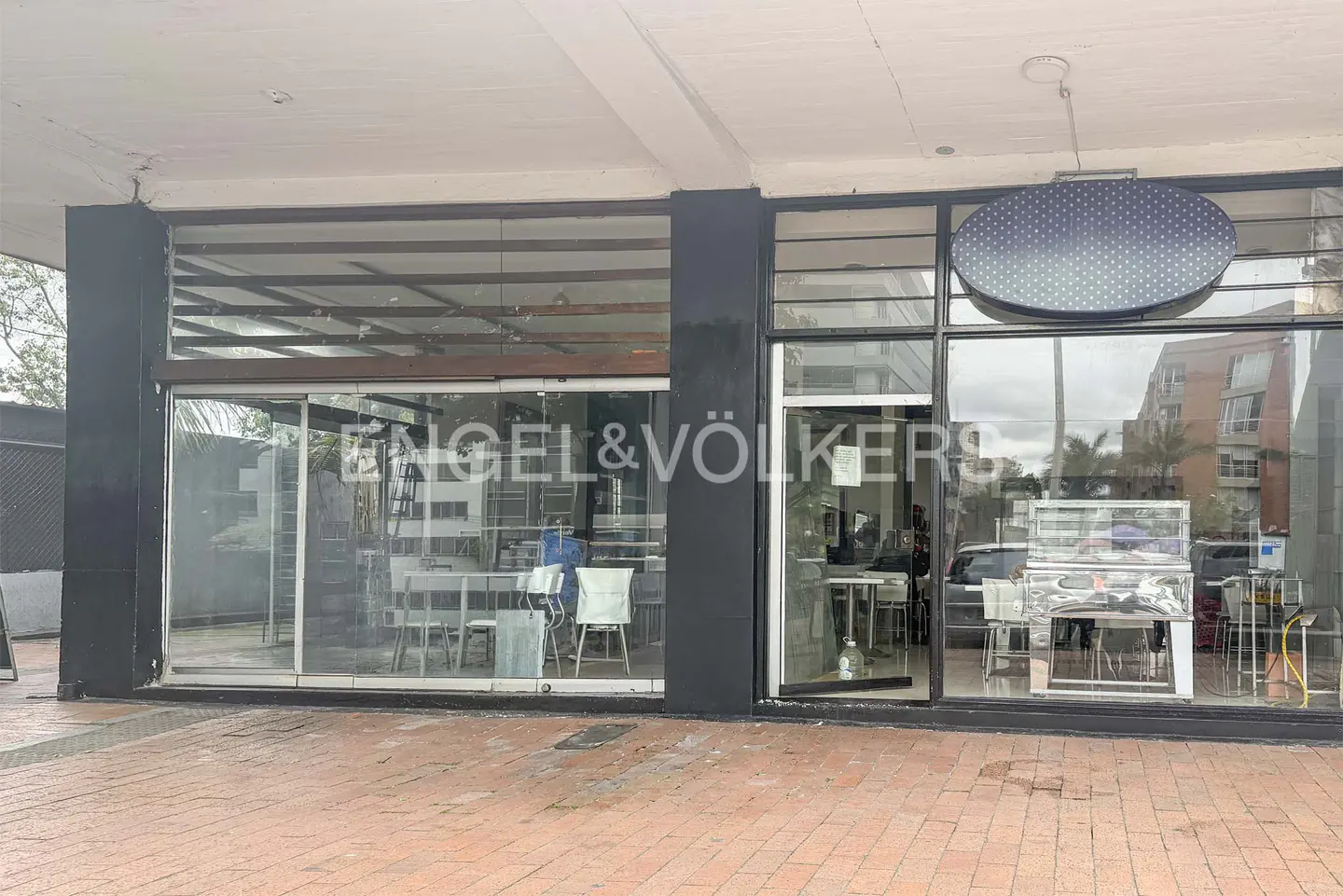 Exterior view of an Engel & Völkers real estate office with large glass windows and a brick sidewalk.