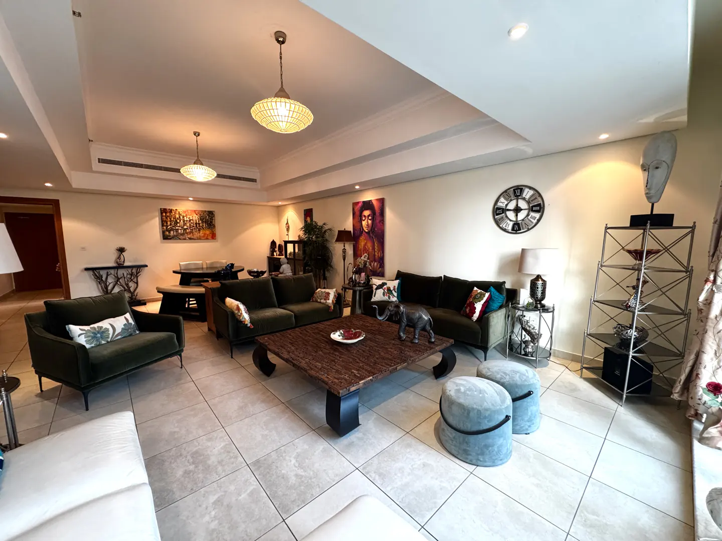 A spacious living room with green sofas, a wooden coffee table, and decorative art.