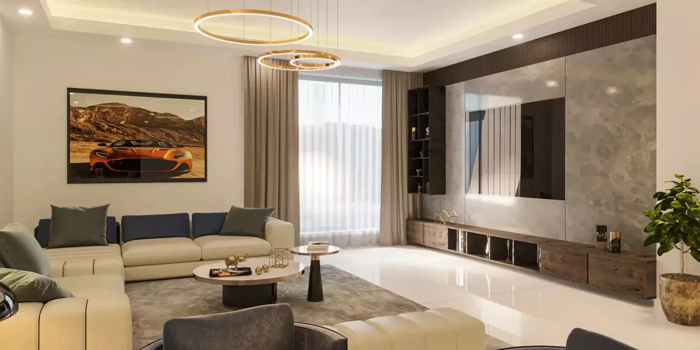 Living room with a cream sectional sofa, round coffee table, and a large framed print of an orange sports car. Modern lighting fixtures hang from the ceiling.
