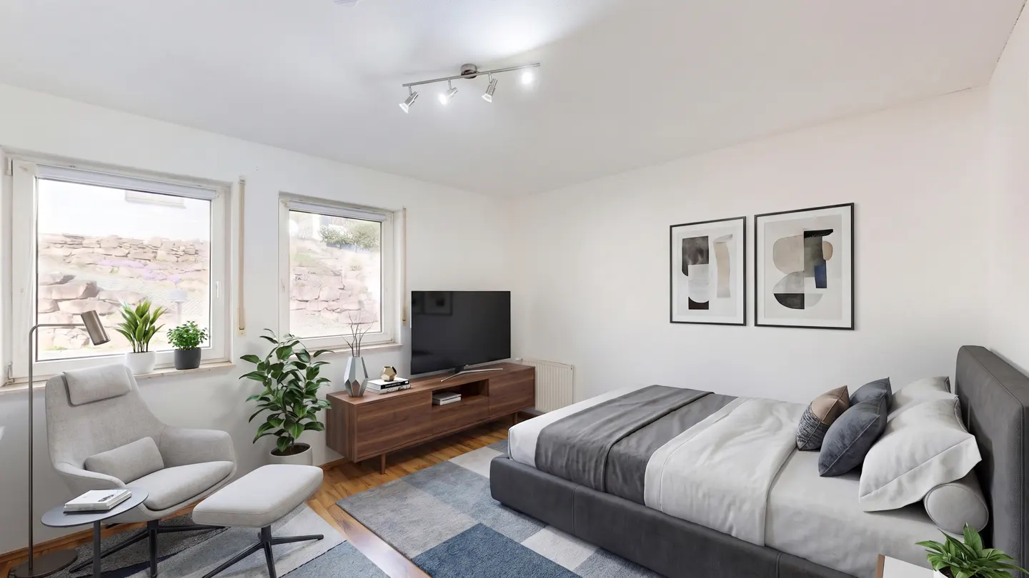 A bright bedroom with white walls, a gray bed, a wooden TV stand, and a gray chair by the window. Two framed abstract art pieces hang on the wall.