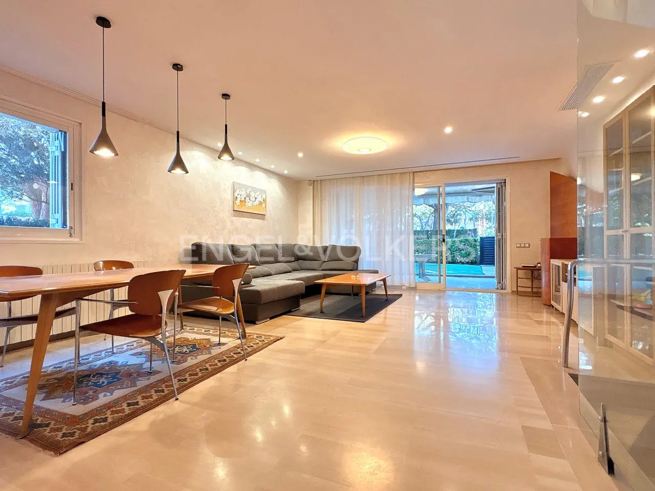 A bright living room with a dining table, gray sectional sofa, and sliding glass doors to a patio.