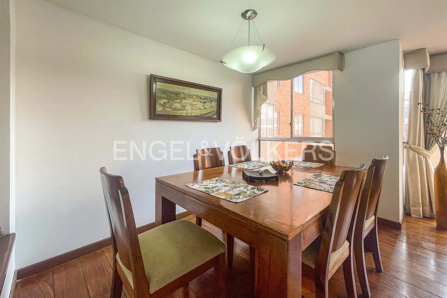A dining room with a wooden table, chairs, and a window with natural light.