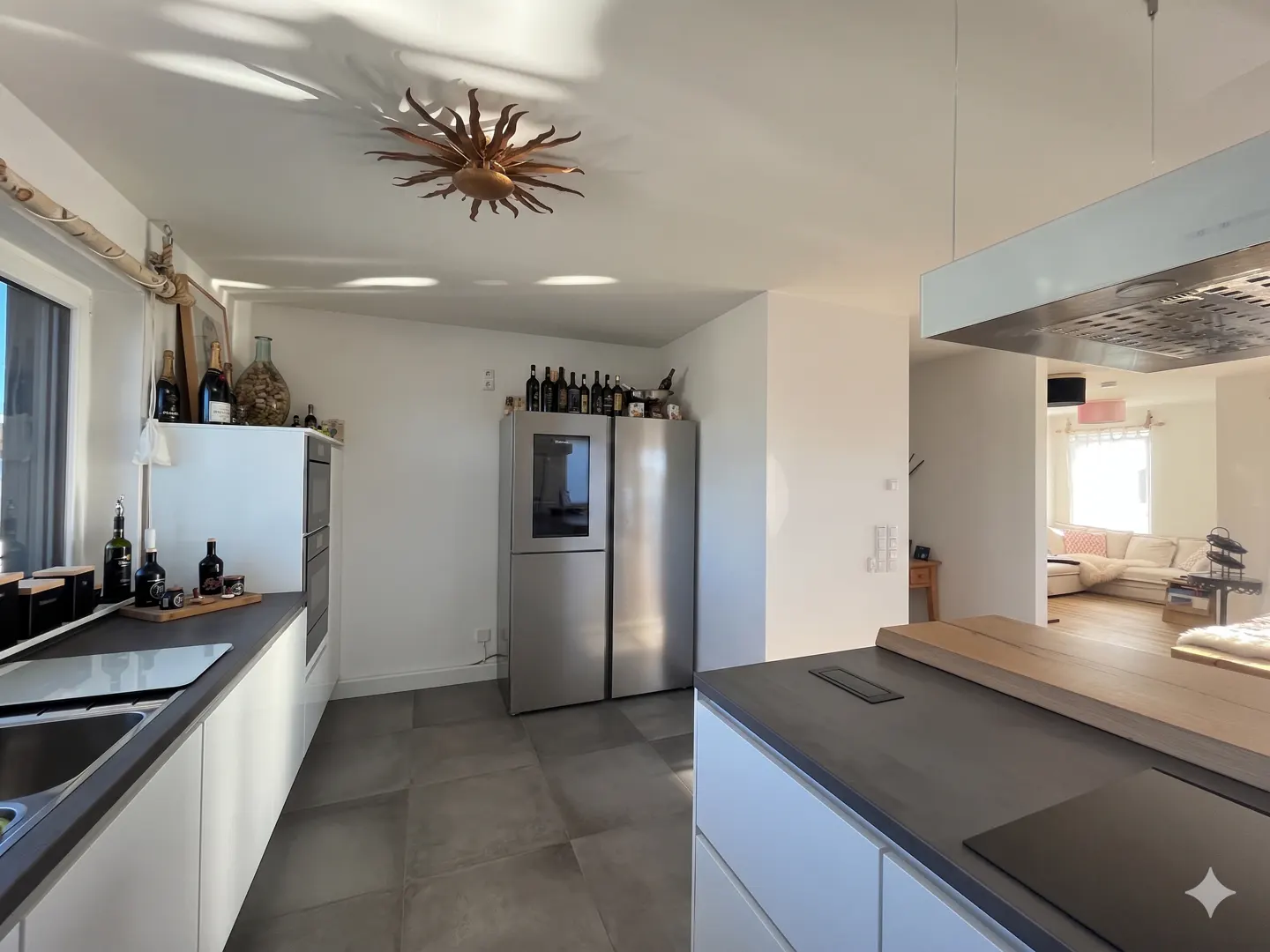 Bright kitchen with white cabinets, gray countertops, and stainless steel appliances. A sunburst light fixture is on the ceiling.