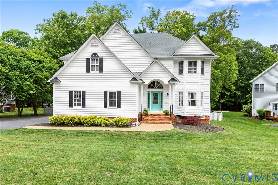 Two-story white house with a teal door, black shutters, and a green lawn. Trees are in the background.