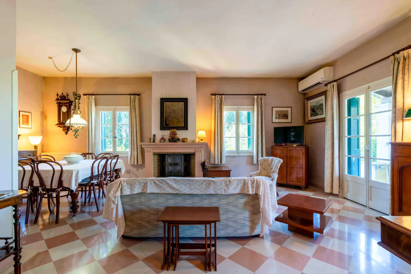 A spacious living room with a dining area, fireplace, and checkered tile floor.