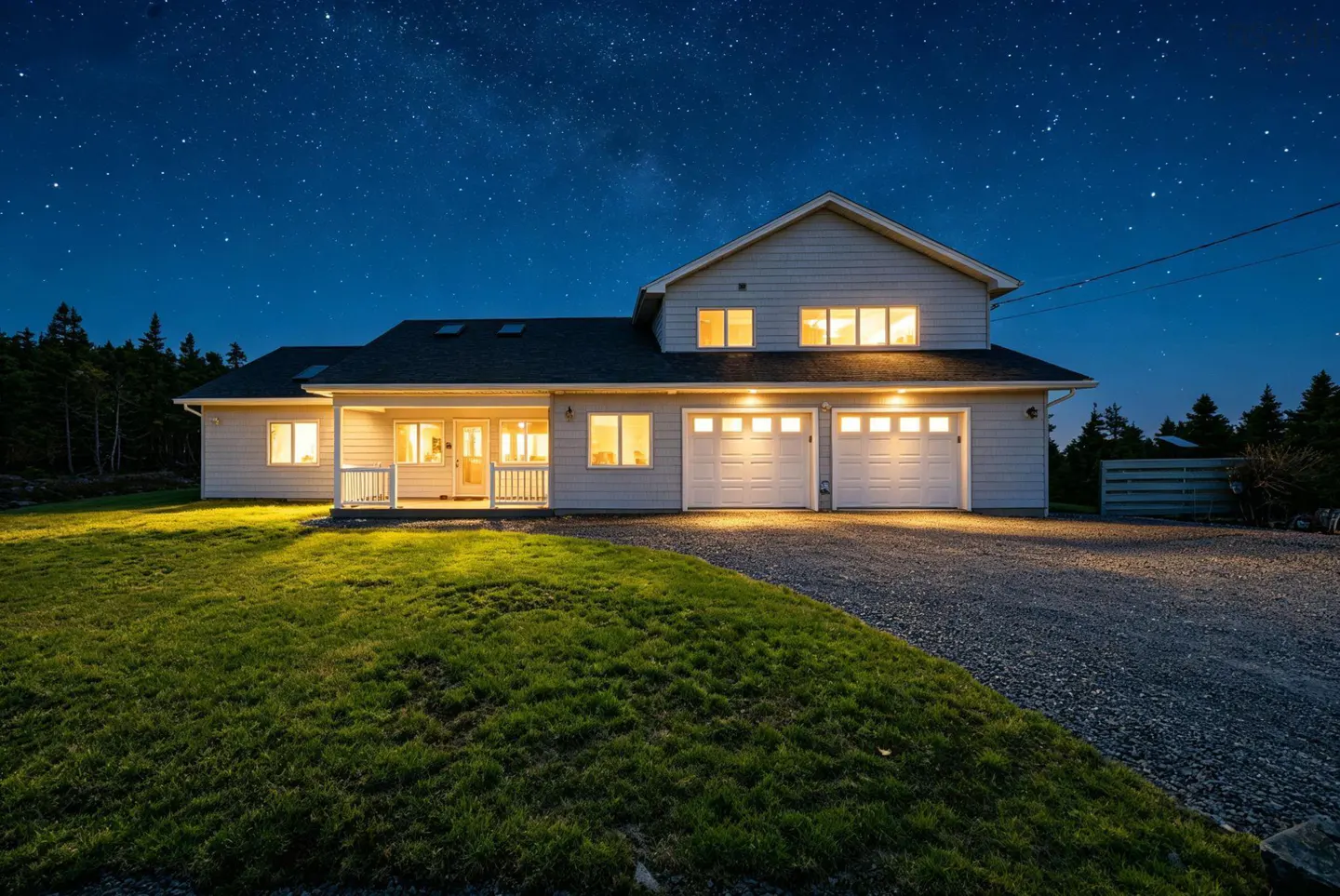 Two-story house with a two-car garage at night. The house is light gray with white garage doors and trim. The sky is dark blue with many stars.