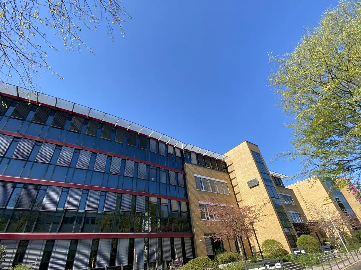 Modern office building with glass and brick facade under a clear blue sky.