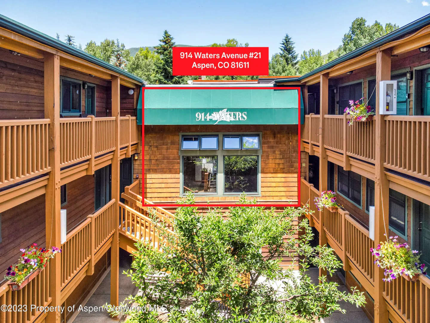 Exterior view of 914 Waters Avenue, Aspen, CO, with wood siding, green awning, and balconies with flower boxes.