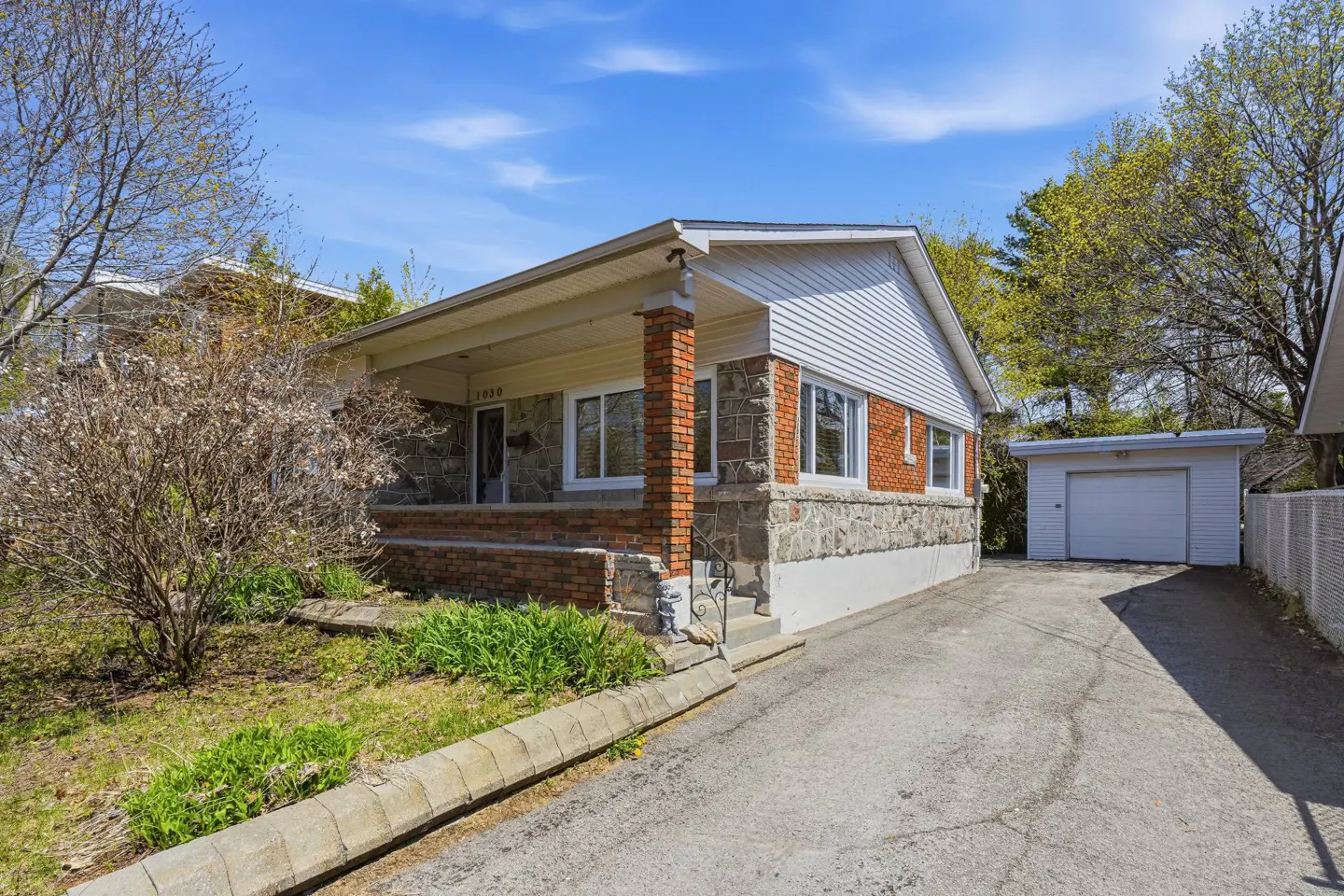 A single-story house with a stone and brick facade, a covered porch, and a white garage.