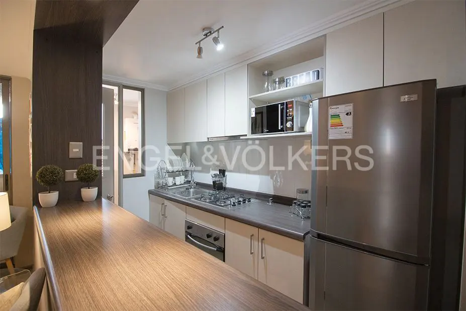 A modern kitchen with light cabinets, stainless steel appliances, and a wooden breakfast bar.