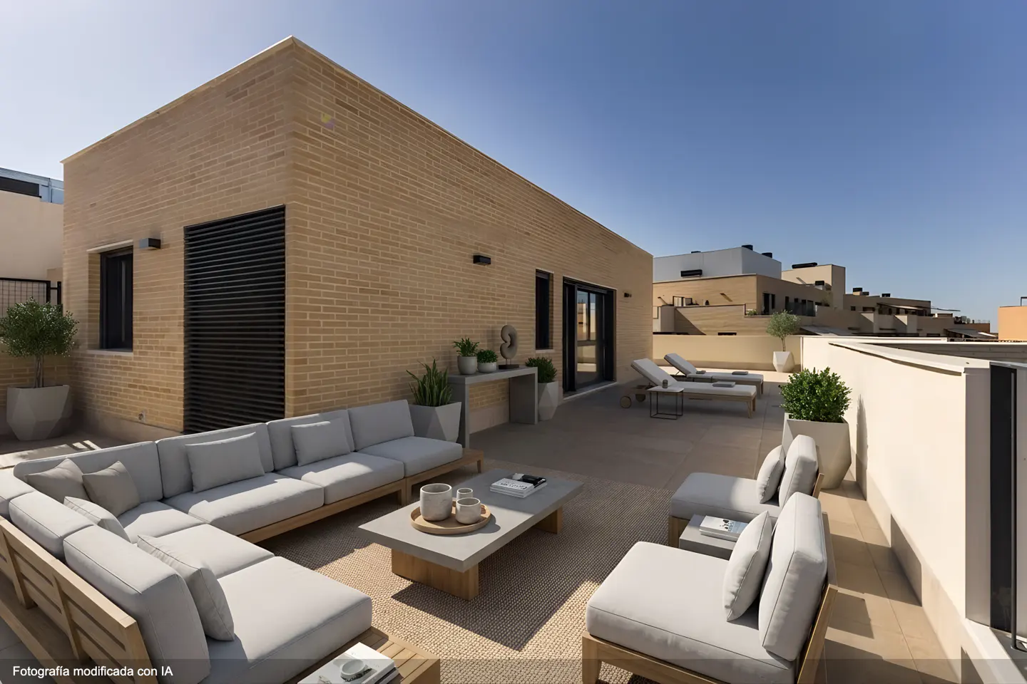 Modern rooftop terrace with light-colored brick walls, a large sectional sofa, lounge chairs, and potted plants.