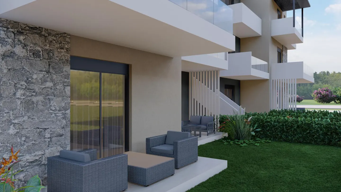 Exterior view of a modern apartment building with gray wicker patio furniture and a green lawn.